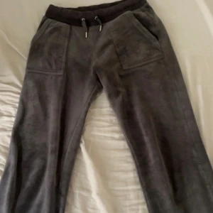 Mörk Grå mjukisbyxor från Juicy Couture - Supermysiga grå mjukisbyxor från Juicy Couture i storlek XS. De har en bekväm passform med snörning i midjan. Perfekta för en avslappnad dag hemma eller bara ett par snygga mjukisbyxor. 🩶