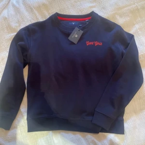 Mörkblå sweatshirt från Gant - Säljer en snygg mörkblå sweatshirt från Gant. Den har en röd broderad text 'Gant Girls' på bröstet och en röd detalj på insidan av kragen. Tröjan är i nyskick och perfekt för både vardag och avslappnade tillfällen. Passar bra till jeans eller chinos!
