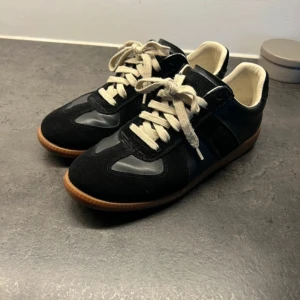 Maison Margiela Skor svarta - Säljer ett par snygga svarta sneakers från Maison Margiela R eplica. Väldigt bra skick.
