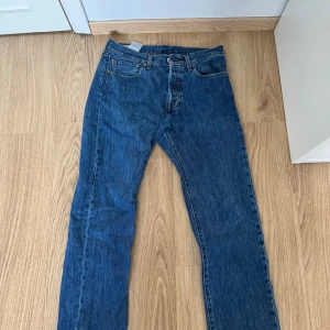 Levi's 501 Jeans - Säljer ett par klassiska Levi's 501 jeans i blå denim. De har en straight passform och är i bra skick. Perfekta för både vardag och fest. Jeansens ikoniska design gör dem tidlösa och lätta att matcha med olika stilar.