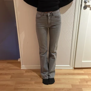 Grå bootcut jeans från Gina Tricot - Säljer ett par snygga grå bootcut jeans från Gina Tricot i storlek 32. De är i bra skick, använda endast 2-3 gånger och har en klassisk femficksdesign med knapp och dragkedja framtill. Perfekta för både vardag och fest! 🖤