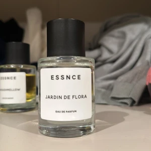 Essnce Jardin de Flora Eau de Parfum - Säljer en elegant och fräsch parfym från Essnce, 'Jardin de Flora'. Flaskan är stilren och genomskinlig med en svart kork. Perfekt för dig som älskar blommiga dofter. Passar både till vardags och speciella tillfällen. 🌸