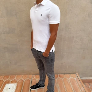 Ralph Lauren Piké - Säljer en stilren vit pikétröja från Ralph Lauren. Den är kortärmad och har en klassisk krage med knappar. Perfekt för både vardag och festliga tillfällen. Tröjan är i bra skick och passar till det mesta i garderoben. 🕶️