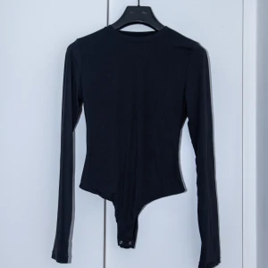 Långärmad ”body hugging” bodysuit - Oanvänd, aldrig testad. Fick hem fel storlek. Denna bodysuit är gjort av ett supermjukt och stretchigt material som anpassar sig efter kroppen. Denna bodysuit är osynlig under kläder och kan bäras i vardagen och vid speciella tillfällen. 