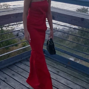 Klänning - Röd klänning som utan band. Den är i storlek xs och är använd 2 gånger på bröllop bara. Klänningen har en slits framifrån som jag sytt ihop då jag tyckte den gick för långt upp, det är möjligt att sprätta upp det om man vill det.  