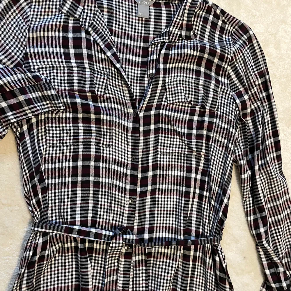 Klänningen är från Lindex och är i storlek L, har endast användes ett få tal gånger. Den är lång, svart, vit och röd och är 100% viscose. . Mekot.