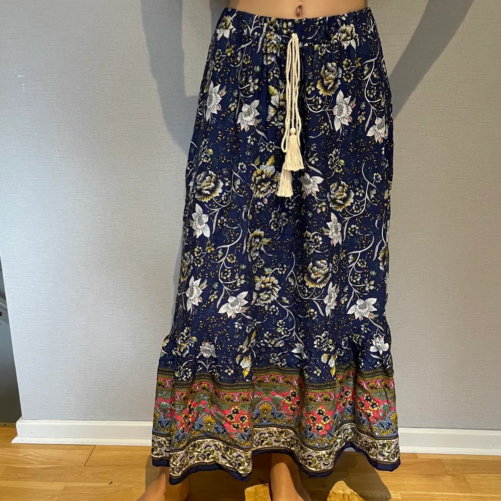 Somrig lång blå kjol med blommigt mönster. Använd endast en gång. Storleken är okänd men skulle gissa på s/xs . Kjolar.