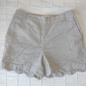 Beigea linneshorts med glitter - storlek 34 - Sjukt fina beigea linneshorts. Vågig kant nertill och fickor i sidorna. Stängs med dragkedja + knapp i sidan. Passpoalfickor i bak. Perfekt beige nyans och med skimmer/glitter. Storlek 34. 50% lin, 40% bomull och 10% metallfiber. Använda bara ett par ggr.