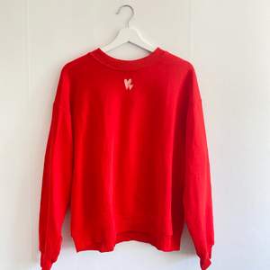 Jättefin röd sweatshirt med två broderade hjärtan på framsidan. Sparsamt använd och inga tecken på slitage. Strl S. Skriv för fler bilder!
