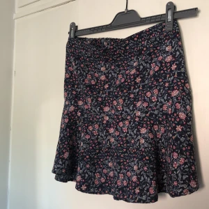 Blommig kjol - Blommig kort kjol i tunt tyg. På baksidan finns resår som gör storleken mer anpassningar. Den är i storlek 34 och kostar 50 kr plus frakt som betalas av köparen!☺️ Hör av dig vid eventuella frågor!