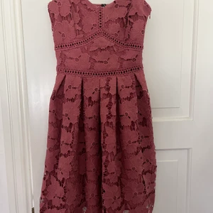 Rosa spets klänning storlek xs  - Superfin klänning med blommig spets. Supersöt och passar perfekt till de lite mer speciella tillfällena. Enbart använd en gång på ett bröllop. Sitter åt i midjan och har en piffig kjol som ger en superfin figur. Har en dragkedja vid midjan! 