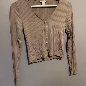 TOPP - Säljer denna beiga fina långarmade tröjan tro den är från New yorker, den har knappar, inte myvker använd säljer den för 50kr storlek Xs men skulle säga att den passar en S med 