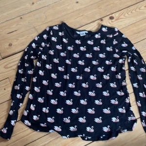 Topp med gulligt tryck  - Säljer en topp från H&M med tryck av rosa svanar. Inte mycket använd så är i fint skick.