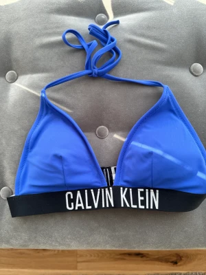 Ck bikini överdel+underdel - Säljer bikini från calvin klein, inte mycket använd. Jättefint skick inga fläckar eller hål. Storlek S. Färgen lite blå/lila