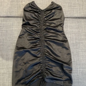 Klänning med scrunch - Jättefin klänning från Nelly med snöre fram så man kan dra ihop scrunchen så klänningen blir mer eller mindre veckig. Aldrig använd i storlek 34.