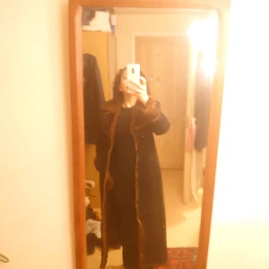 Kappa av äkta läder ( - Det är lång och i läder och i bra skick den är svart utan för och brun päls inne foder 