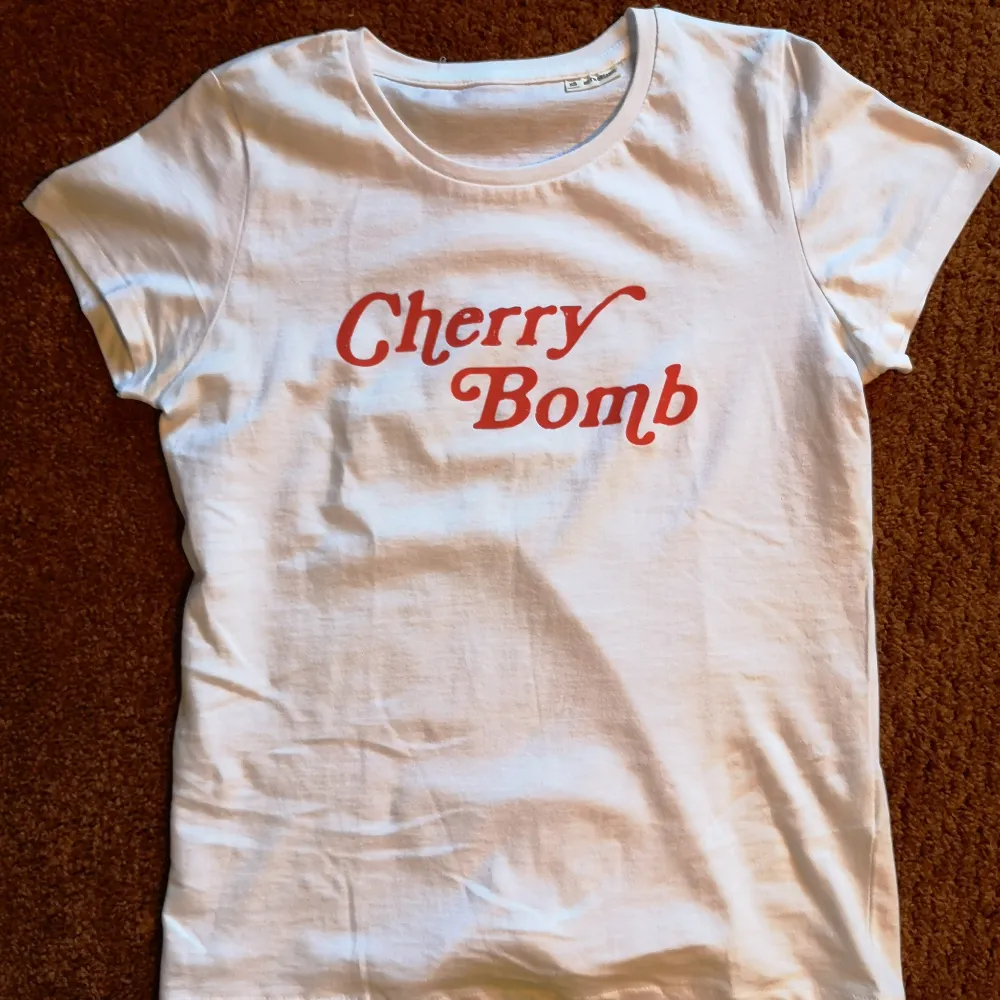 Cherry Bomb T-shirt  Tjej-modell i 100% bomull, 145g/m2 säljes. Made in Sweden! Limiterad antal! Ingen Massproduktion.  Bystmått : 49cm  Längd ( baksida ) : ca 60cm More sizes at elcamelloshop.com . T-shirts.