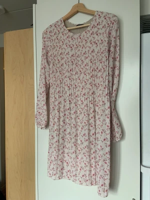 Blommönstrat klänning  - Babyrosa, blommönstrat klänning med långa ärmar. 