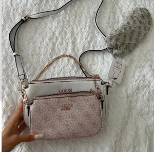 Guess mika crossbody väska pouch ny rosa vit - Guess  Använd en gång inomhus - annars helt ny enligt bild  Nypris: 1200kr, inköpt i juli Kvitto finns - köpt på guess hemsida
