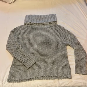 Stickad tröja  - En ljusgrå stickad tröja med bred krage. 