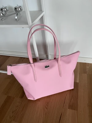 Lacoste stor väska / handväska - Shoppingvecka Lacoste (kopia). Oanvänd.  Ca 35 cm bred. Står mot ett avkastningsmodeller för att se realistisk storlek.