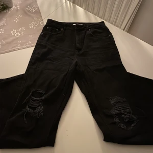 Jeans NA-KD (strl. 42) - Svarta jeans med hål vid knäna i storlek 42 från NA-KD. Nypris ca 500kr och är väl använda. Bra skick! Pris kan diskuteras!