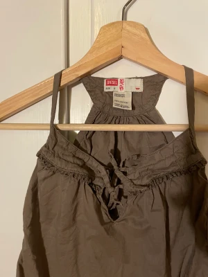Diesel topp - En liten top från diesel i olivgrön färg, med många fina detaljer. Väldigt liten i storlek men går att knäppa up. Troligen i barnstorlek 