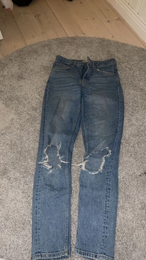 Straight jeans - Blåa straight jeans med hål på knäna. Det är använda några gånger men är i bra skick