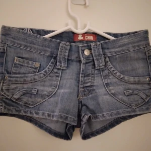Jeansshorts. Strlk: 25 midjan / XS. Mellanblå. Fint skick. - Jeansshorts.  Strlk: 25 midjan / XS.   Mått: Ca 78 cm total omkrets i midjan. Låg/Low/normal midja. Mellanblå.  Knappt använda, fint skick, inga fel. FRAKT TILLKOMMER.