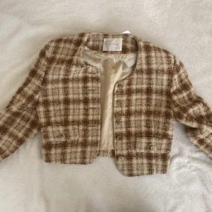 Beige tweedjacka - 90s Chanel-esque kort tweed jacka med vadderade axlar. Köpt secondhand så små tecken av bruk finns, skickar gärna bild vid förfrågan.