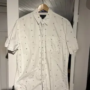 Kortärmad, vit skjorta med detaljer i storlek M. Knappast använd och i mycket bra skick