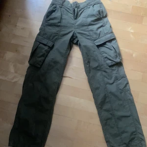 Cargo pants - Gröna cargopants.  På bilden har jag vikt ner de i midjan så att de är low waist, men uppvikta är de lite under naveln. De är från hm i strl 34 men jag har strl 36 på mina jeans där ifrån. De är alltså töjbara med mudd i midjan. Mötas upp kan diskuteras.