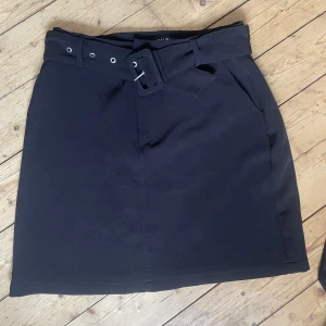 Svart kostym-kjol - Svart kostym-kjol från Newyorker med bälte i midjan. Midwaist. Använd en gång. Längd: mitten på låren. 