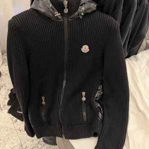 Moncler cardigan - Moncler cardigan storlek xxl (sitter som m-L). Väldigt fint skick på jackan förutom att det finns en liten lagning på jackans arm som man inte direkt tänker på. Vid frågor är det bara att skriva