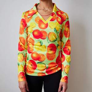 En silkig tröja i polyester med citrusfrukter på, passar både S och M. Stretchig!