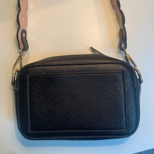 söt liten väska - Säljer min söta lilla svarta väska från Gina med gulddetaljer som man kan byta väskband till. Säljer för 150kr