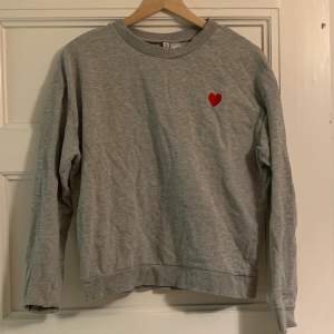 En grå tröja med ett hjärta från HM. Storlek M. Använd fåtal gånger. 60kr + frakt (cirka 50kr)