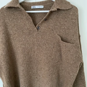Stickad tröja - Säljer denna stickade tröja med ficka på bröstet och svarta knappar vid kragen från Zara, använd 2 gånger och är i nyskick😊