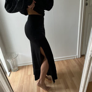 Lång svart kjol med slitt  - Svart kjol från Nelly. Storlek XS. Använt 2 gånger. Kjolen är stretch så går att använda om man är storlek S också. Köparen står för frakt. ( jag är 159 cm lång ) 