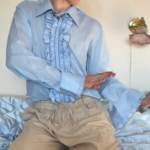 Ljusblå skjorta oversized krås volang  - Vintage 70-tals ljusblå oversized skjorta med krås och volang 👔 Så snygg nu till sommaren till en uppklädd outfit eller med en t-shorts under för en avslappnad look! Älskar sömdetaljerna på kråset och att de är mörkblåa så att det blir en form av contrast stitching! :D