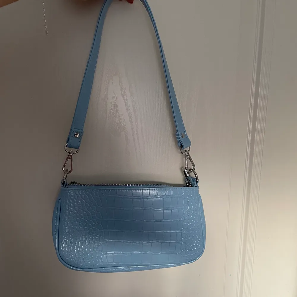 Jättefin blå handväska från Gina tricot. Köpt förra sommaren men endast använd ett fåtal gånger och ser därav fortfarande ut som ny. Köpt för 300kr, säljer nu för 149kr. Krokodiltextur (ej riktigt). Avtagbart axelband. Passar jättefint till en vår- eller sommaroutfit. . Väskor.