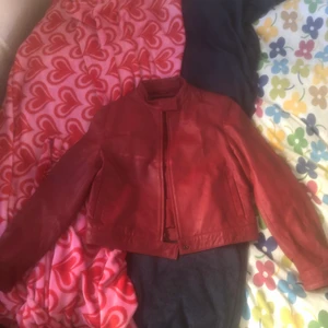 röd Skinnjacka  - Jag säljer denna röda skinnjacka eftersom att jag inte har fått användning av den.köpte den på loppis i sommras. Storleken är L men skulle säga att den sitter bra på någon som är xs-L. Köpare står för frakt.