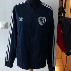 Blå adidas zip up med kansas city sporting på. Köpt på beyond retro.