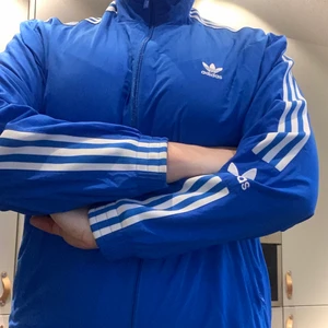 Adidas blå jacka 38 - Snygg jacka från adidas. Har bara använt den några gånger till vardags (inte träning!). Den sitter lagom tight på mig. Jag är 1,70 och väger 70 kg. Skulle säga att den är som en stor 38:a.