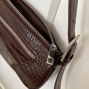 Väska  - Brun axelremsväska i ormskinn, köpt på bikbok för ca 2 år sedan men knappt använt den så den är i mycket bra skick inga spår av användning! 