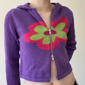 UNIF Dazee kofta  - Lila stickad kofta/hoodie med blomma från märket UNIF. Modellen heter Dazee och är köpt från UNIFS egna sida för 850kr + frakt och tull. Aldrig använd endast testad. Storlek small sitter true to size. Jag brukar ha small/36 i toppar och är 171 cm lång. Mått från armhåla till armhåla 50 cm, länge från axel till nedre sömnad 50 cm. Kan mötas upp på södra sidan av stockholm annars står köparen för frakt 66kr. Skriv vid frågor 💌