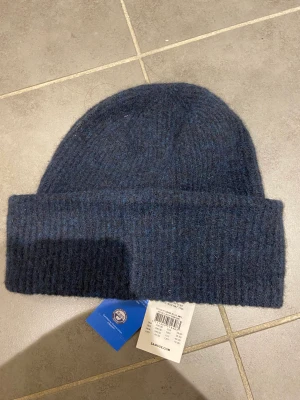 Mössa - Säljer denna skit fina blå stickade mössa från Samsoe samsoe. Aldrig använda, lappen kvar! Perfekt nu då den är stickad men öndå lite tunnare