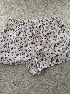 Vita shorts med röda blommor på, tunna i materialet och perfekt till sommaren!