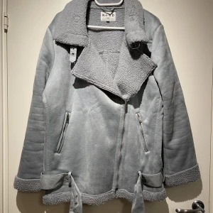 Ljusblå Aviator Jacka - Blå aviator jacka i fake mocka från NA-KD. Storlek 40. Den är endast använd några fåtal gånger så i väldigt fint skick! Se sista bilderna för produktbilder, hur den sitter på.   Finns att hämta upp i Högdalen! Kan även skickas!