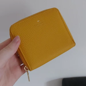 Plånbok - En gul plånbok med dragkedja. Det finns plats för kort, lösa sedlar och mynt. (I nytt skick) pris kan diskuteras